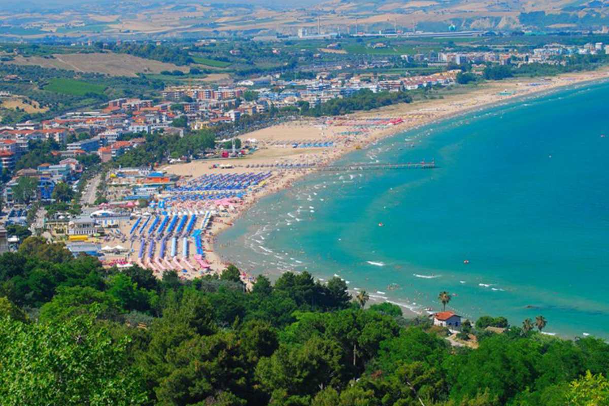 Scorcio della stazione ferroviaria di Vasto-San Salvo con treno regionale in arrivo, fondo colline e mare, atmosfera accogliente mattutina